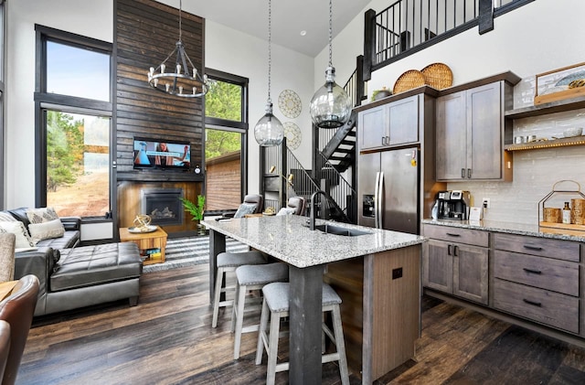 kitchen featuring light stone countertops, sink, a breakfast bar area, hanging light fixtures, and stainless steel refrigerator with ice dispenser