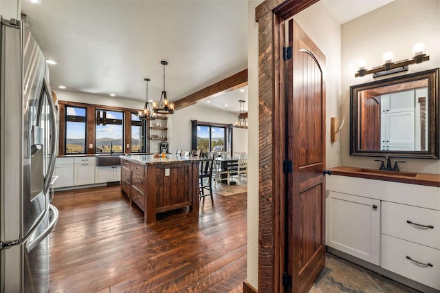 kitchen with stainless steel fridge, sink, white cabinetry, a center island, and dark hardwood / wood-style flooring