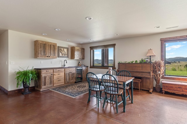 dining room featuring a mountain view, wine cooler, sink, and a textured ceiling