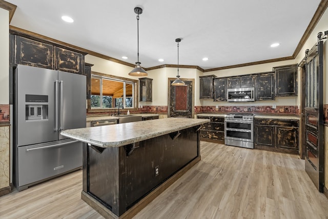 kitchen featuring light wood-type flooring, a center island, stainless steel appliances, sink, and pendant lighting