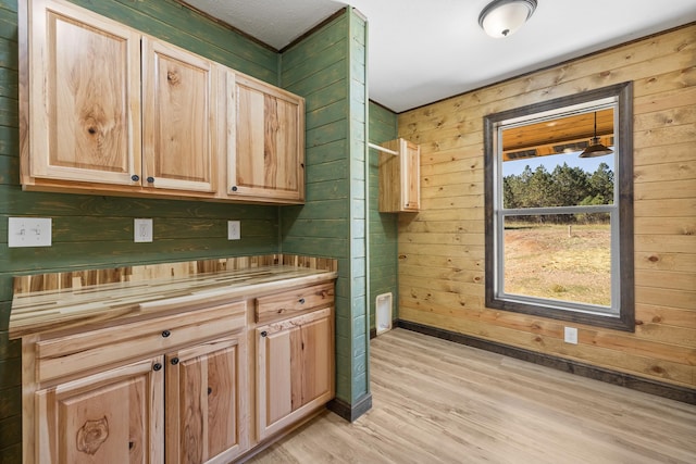 interior space featuring light brown cabinetry, wooden walls, pendant lighting, and light hardwood / wood-style flooring