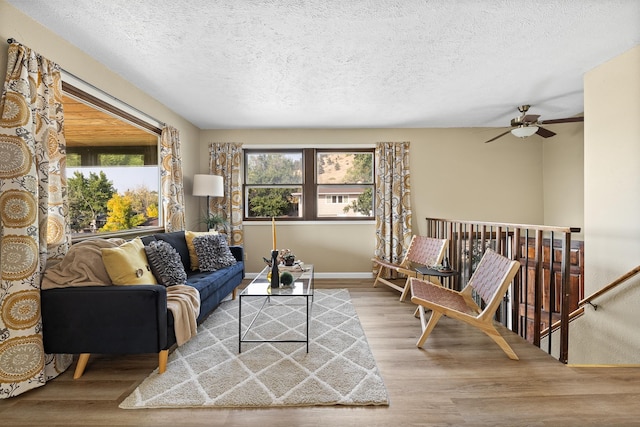 living room with ceiling fan, wood-type flooring, and a textured ceiling