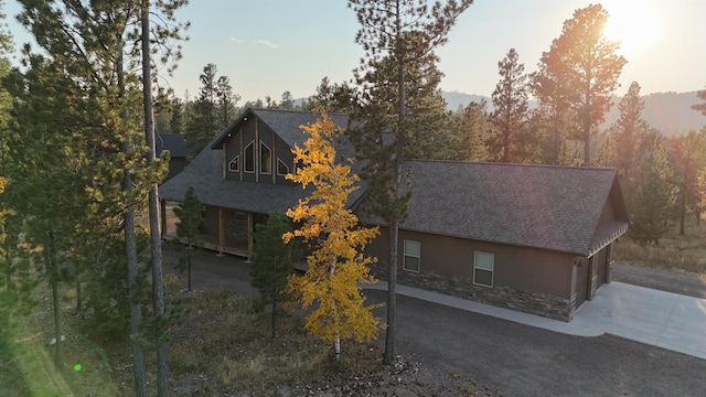 view of front facade featuring roof with shingles and driveway