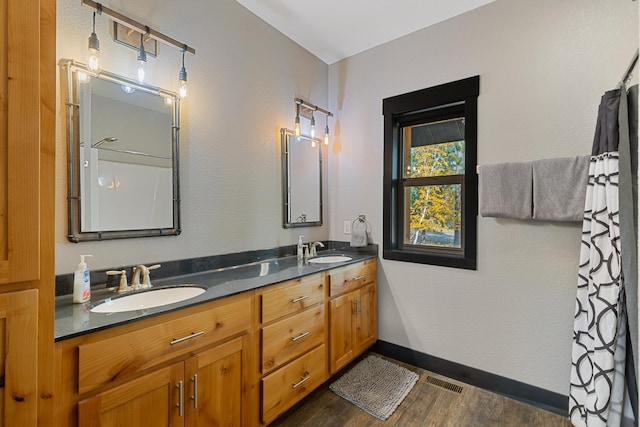 bathroom featuring baseboards, visible vents, a sink, and wood finished floors