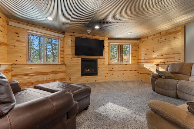 carpeted living room featuring a large fireplace, plenty of natural light, and wood walls