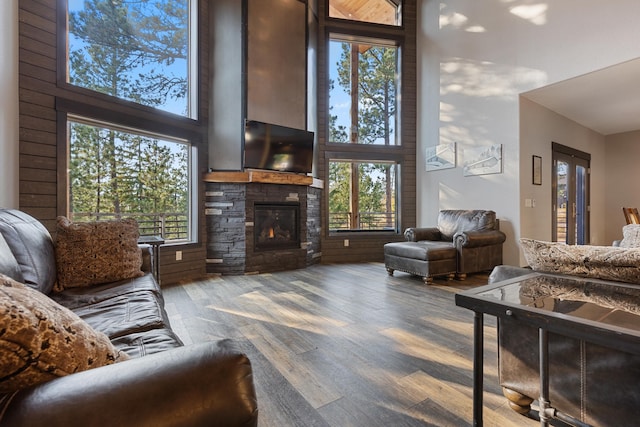 living room featuring a fireplace, wood walls, hardwood / wood-style floors, and a towering ceiling