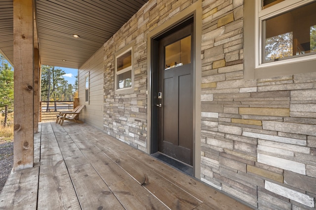 view of exterior entry with a porch and stone siding