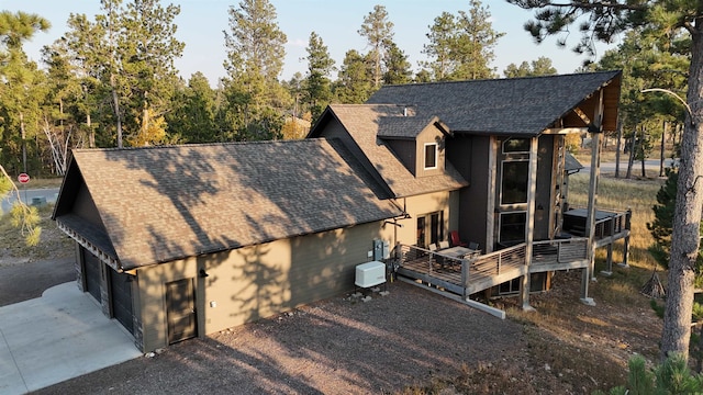 view of home's exterior with roof with shingles and a wooden deck