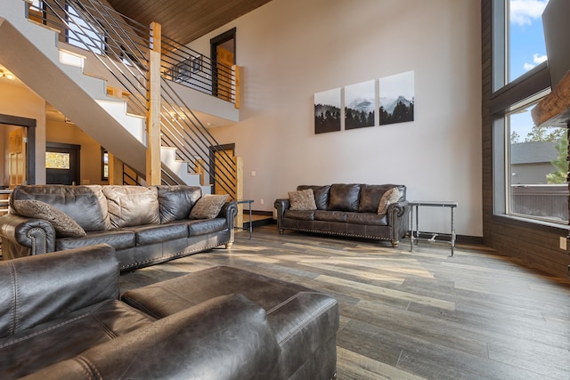 living area with stairs, a high ceiling, wood finished floors, and baseboards