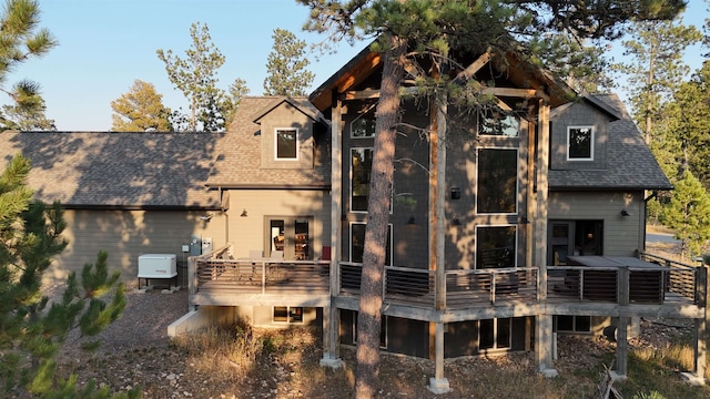 back of house with a shingled roof and a wooden deck