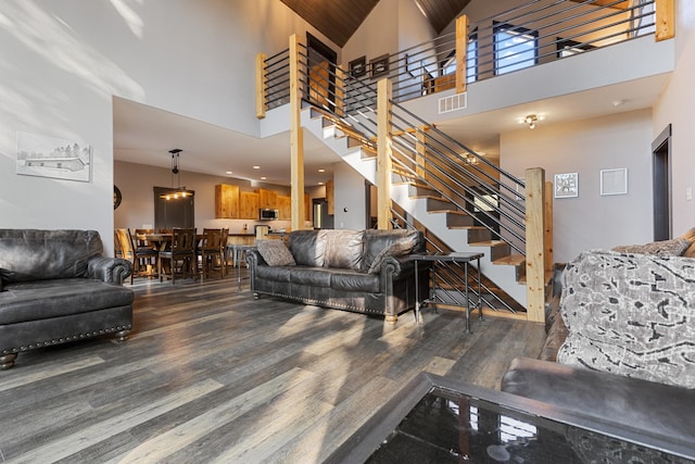 living area featuring stairway, a high ceiling, visible vents, and wood finished floors