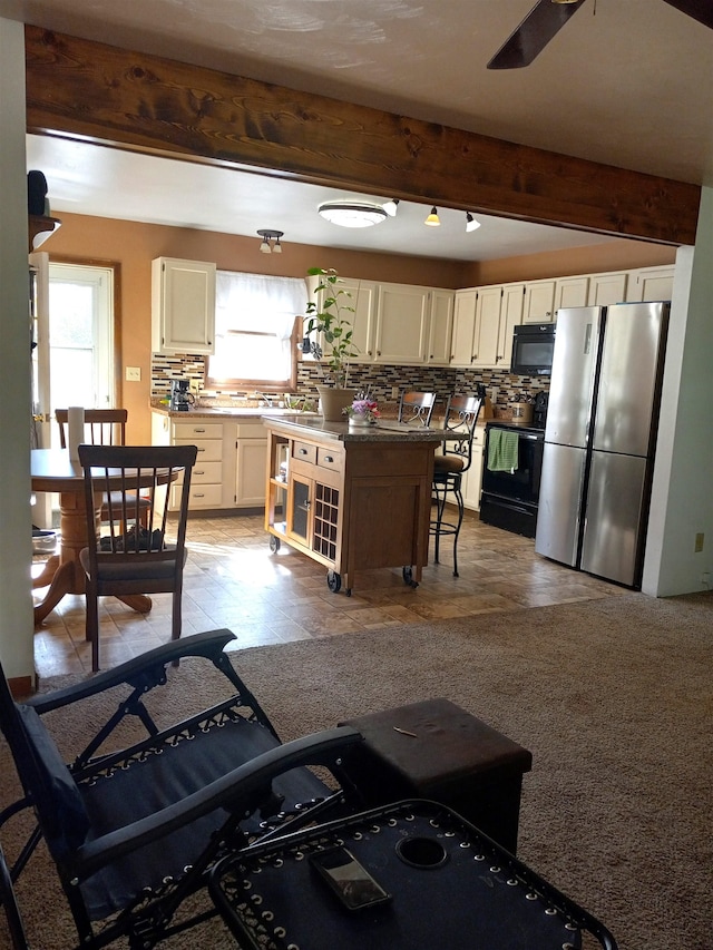 kitchen featuring beamed ceiling, tasteful backsplash, a kitchen island, a breakfast bar area, and black appliances