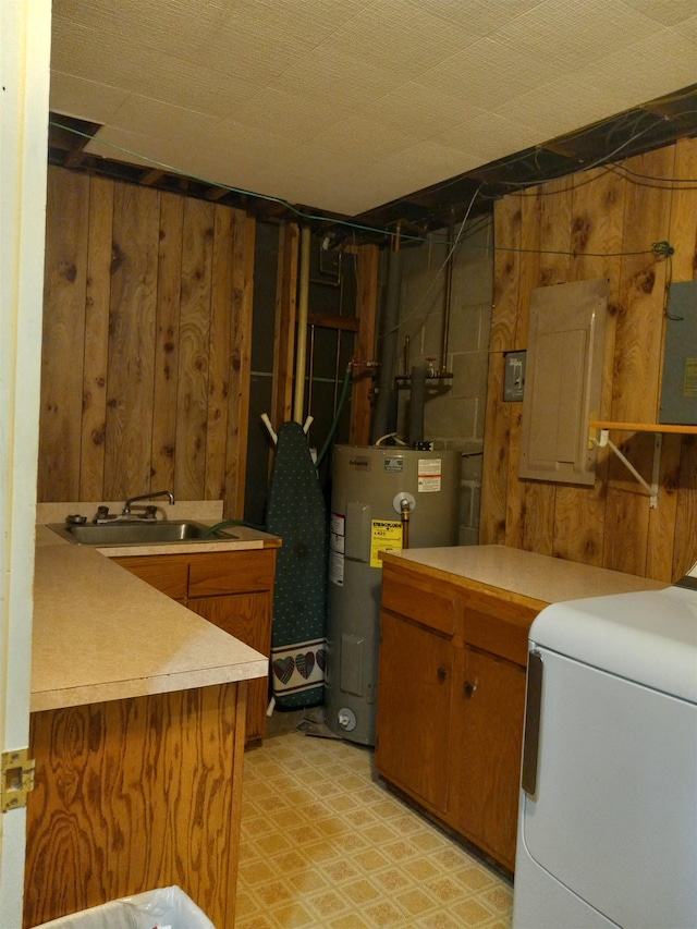 laundry area featuring electric panel, electric water heater, sink, wooden walls, and washer / clothes dryer