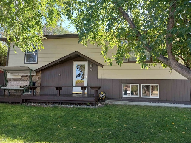 rear view of property featuring a wooden deck and a yard