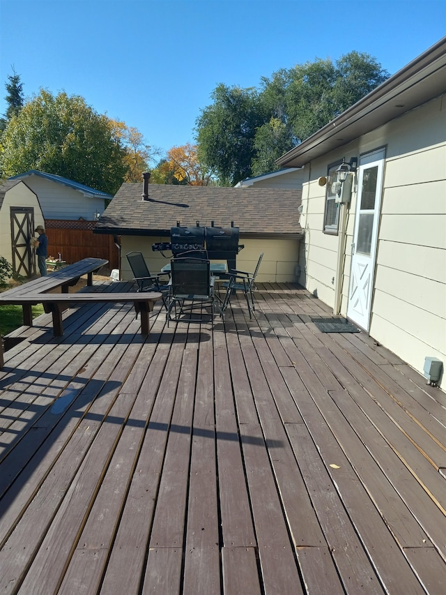 deck with a storage unit and a grill