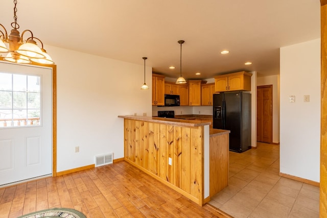 kitchen featuring kitchen peninsula, black appliances, decorative light fixtures, and light hardwood / wood-style floors