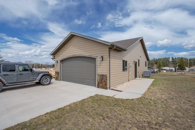 view of side of property with a yard, cooling unit, and a garage