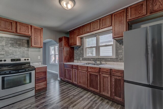 kitchen with appliances with stainless steel finishes, sink, hardwood / wood-style floors, and backsplash