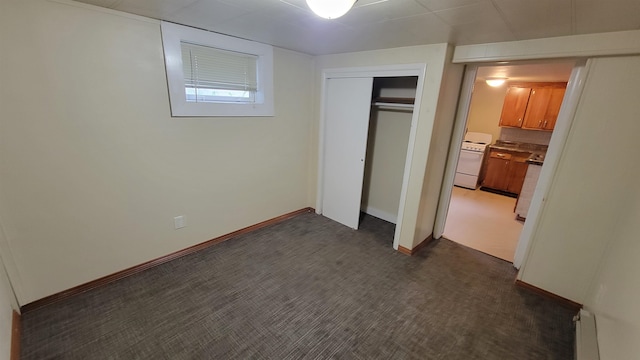 unfurnished bedroom with a closet, dark colored carpet, and a baseboard heating unit