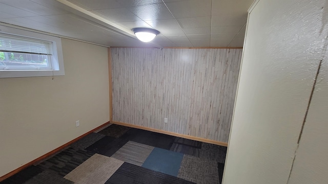 basement featuring wooden walls and dark colored carpet