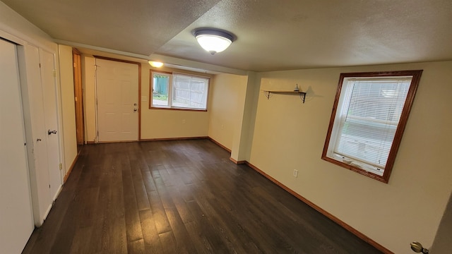 basement featuring a textured ceiling and dark hardwood / wood-style floors