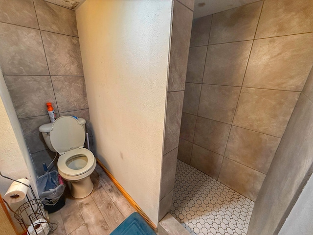 bathroom with tiled shower, hardwood / wood-style floors, and toilet