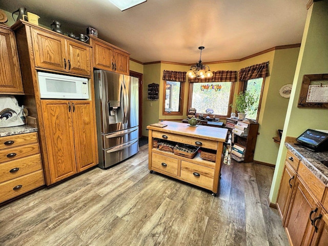 kitchen with hanging light fixtures, light hardwood / wood-style floors, a notable chandelier, ornamental molding, and stainless steel fridge with ice dispenser