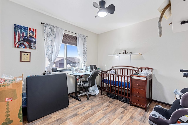 bedroom featuring a crib, light wood-type flooring, and ceiling fan