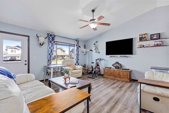 living room with light hardwood / wood-style floors, ceiling fan, and vaulted ceiling