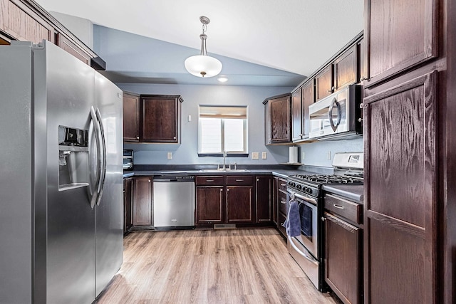 kitchen with sink, vaulted ceiling, pendant lighting, light wood-type flooring, and appliances with stainless steel finishes