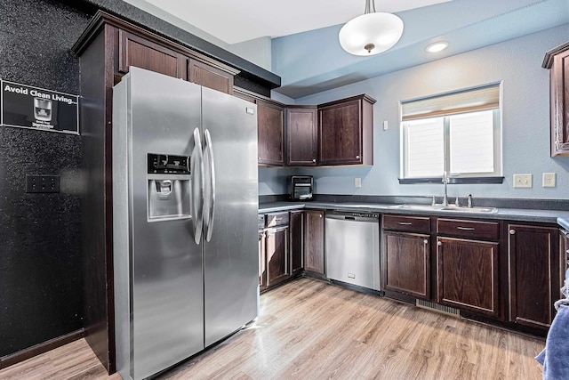 kitchen with appliances with stainless steel finishes, sink, hanging light fixtures, light hardwood / wood-style floors, and dark brown cabinetry