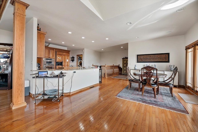 dining room featuring light hardwood / wood-style flooring, sink, and ornate columns