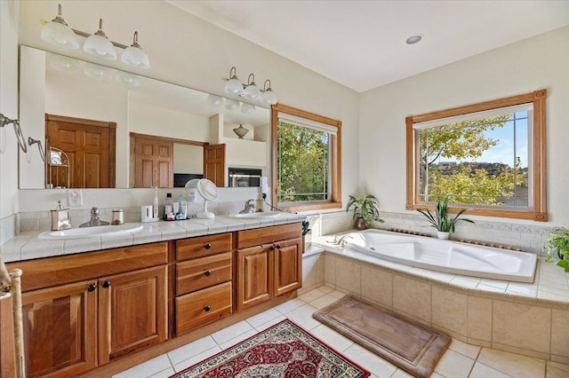 bathroom featuring vanity, a relaxing tiled tub, and tile patterned floors