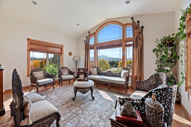 sitting room with lofted ceiling, light hardwood / wood-style flooring, a mountain view, and a healthy amount of sunlight