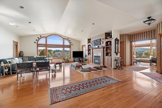 living room with a wealth of natural light, lofted ceiling, and light wood-type flooring