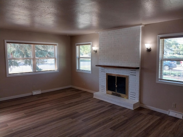 unfurnished living room featuring a fireplace, a textured ceiling, and dark hardwood / wood-style flooring