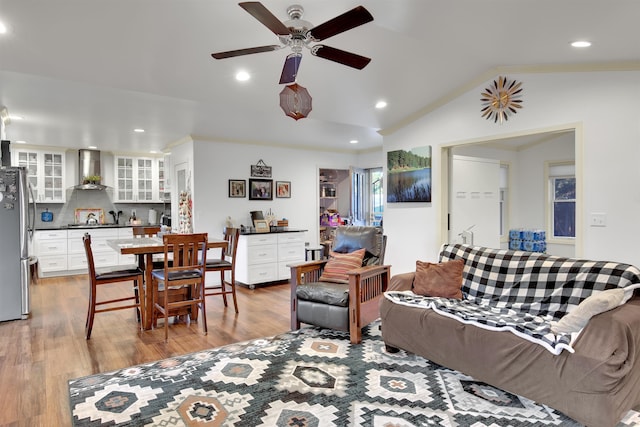 living room featuring lofted ceiling, crown molding, light wood-type flooring, and ceiling fan