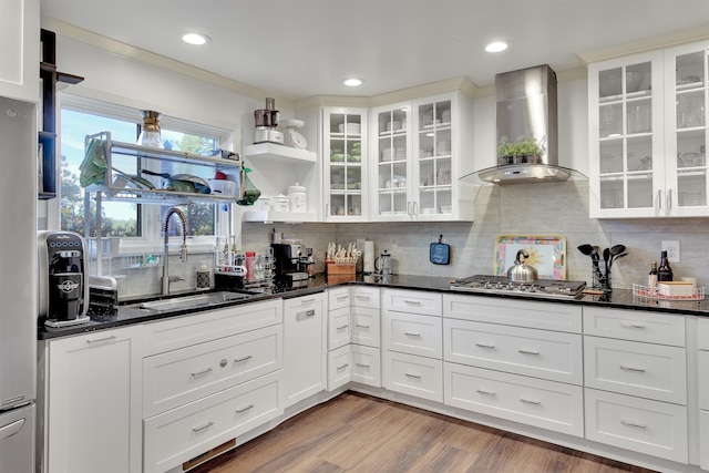 kitchen featuring tasteful backsplash, wall chimney range hood, sink, white cabinetry, and stainless steel gas stovetop