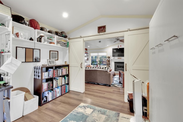 interior space with a barn door, light wood-type flooring, and vaulted ceiling