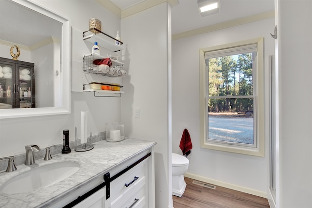 bathroom with vanity, crown molding, wood-type flooring, and toilet