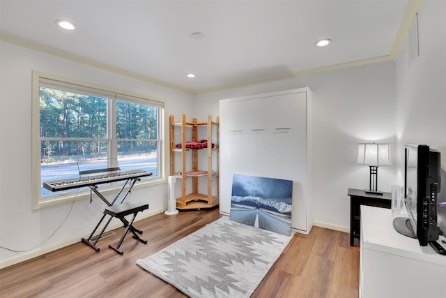 living area with ornamental molding and light hardwood / wood-style flooring