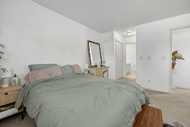 bedroom featuring connected bathroom, light colored carpet, and a closet