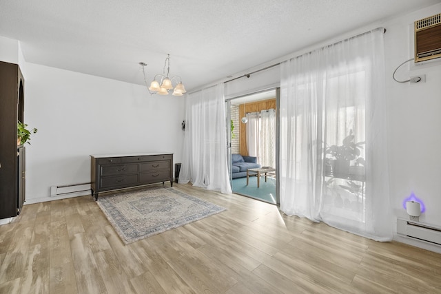 interior space with an inviting chandelier, light hardwood / wood-style flooring, a baseboard heating unit, and a textured ceiling