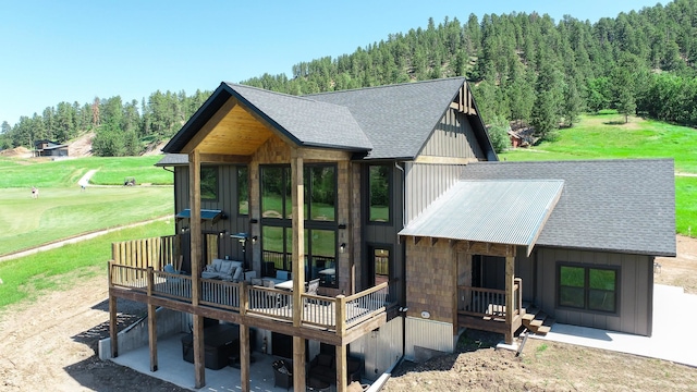 back of property featuring a deck and a lawn