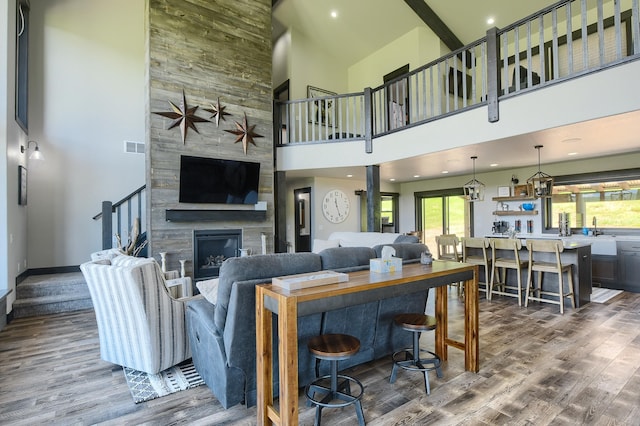 living room with hardwood / wood-style floors, high vaulted ceiling, sink, and a fireplace