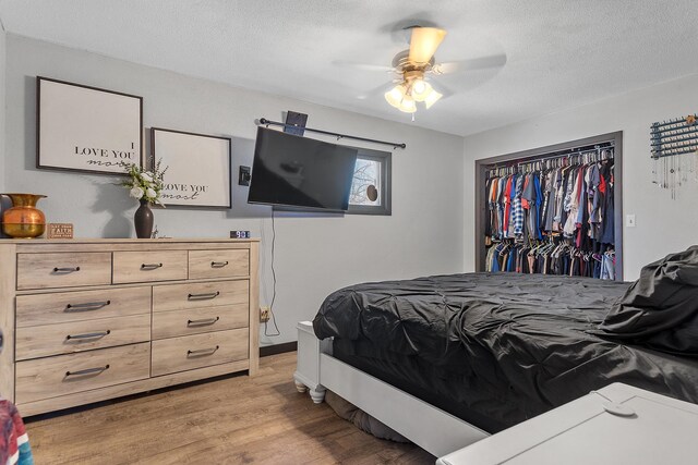 bedroom featuring a closet, a textured ceiling, light wood-type flooring, and ceiling fan