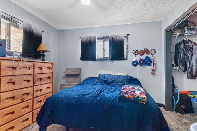 bedroom featuring a closet, ceiling fan, hardwood / wood-style flooring, and a textured ceiling