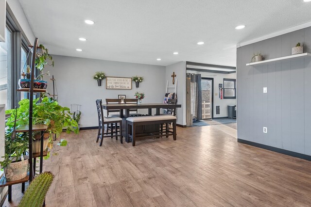 dining room featuring wooden walls, a textured ceiling, and light wood-type flooring