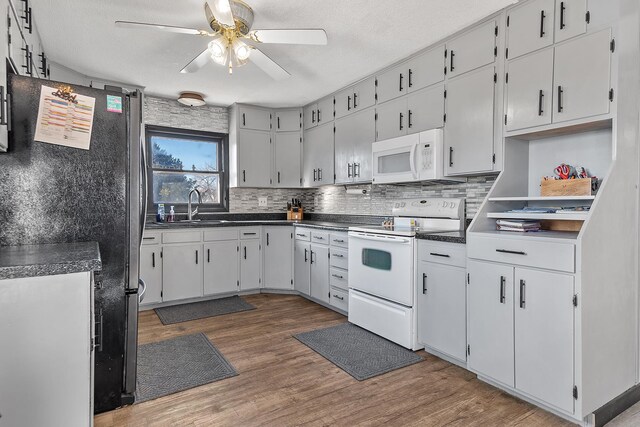 kitchen with dark wood-type flooring, white cabinets, white appliances, and ceiling fan