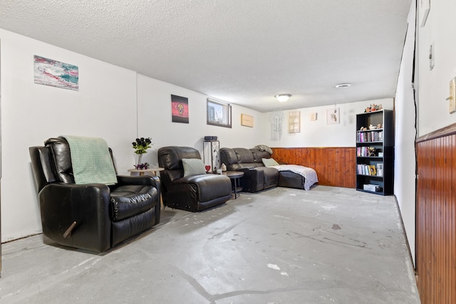 living area featuring concrete floors, wood walls, and a textured ceiling